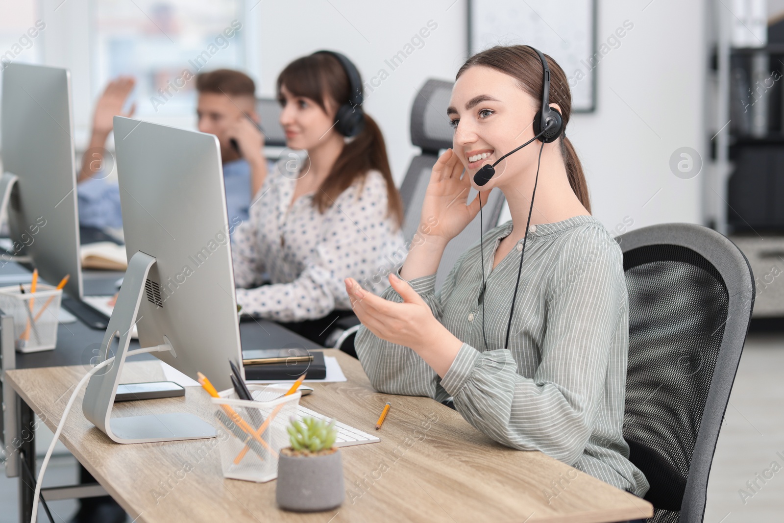 Photo of Saleswoman talking to client via headset at desk in office