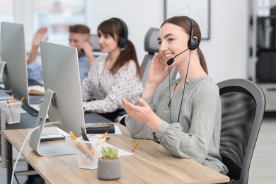 Photo of Saleswoman talking to client via headset at desk in office