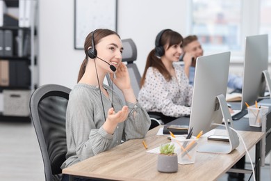 Photo of Saleswoman talking to client via headset at desk in office