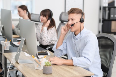 Photo of Salesman talking to client via headset at desk in office