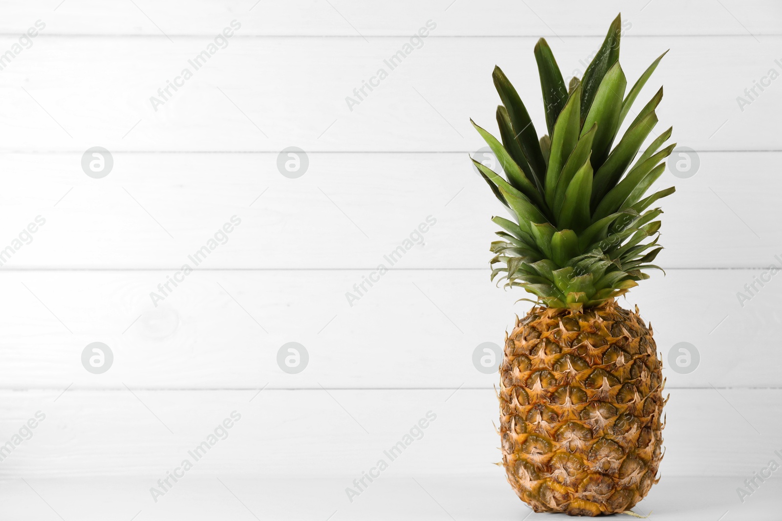 Photo of One fresh ripe pineapple on white table, space for text