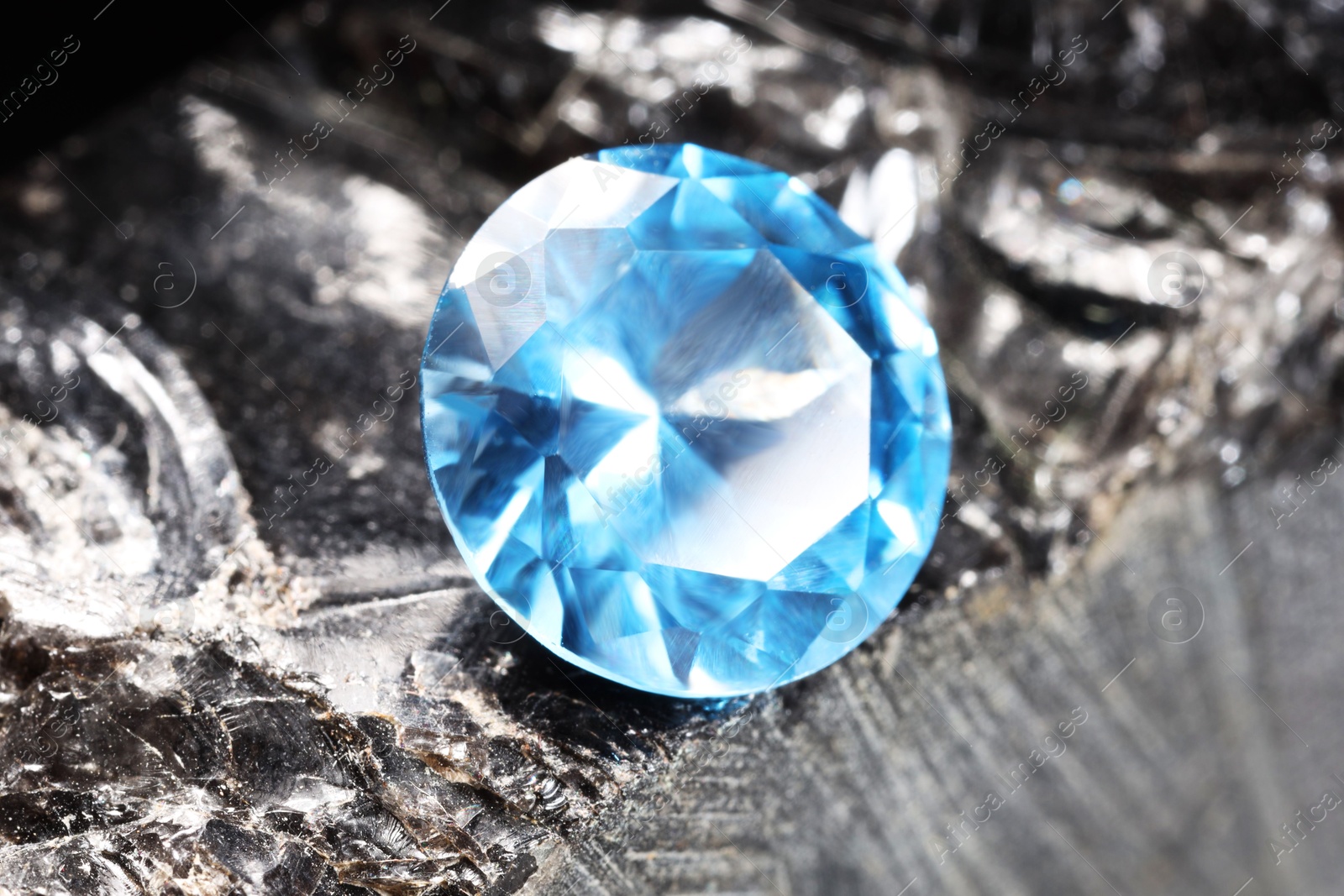 Photo of Beautiful shiny light blue gemstone on stone, closeup