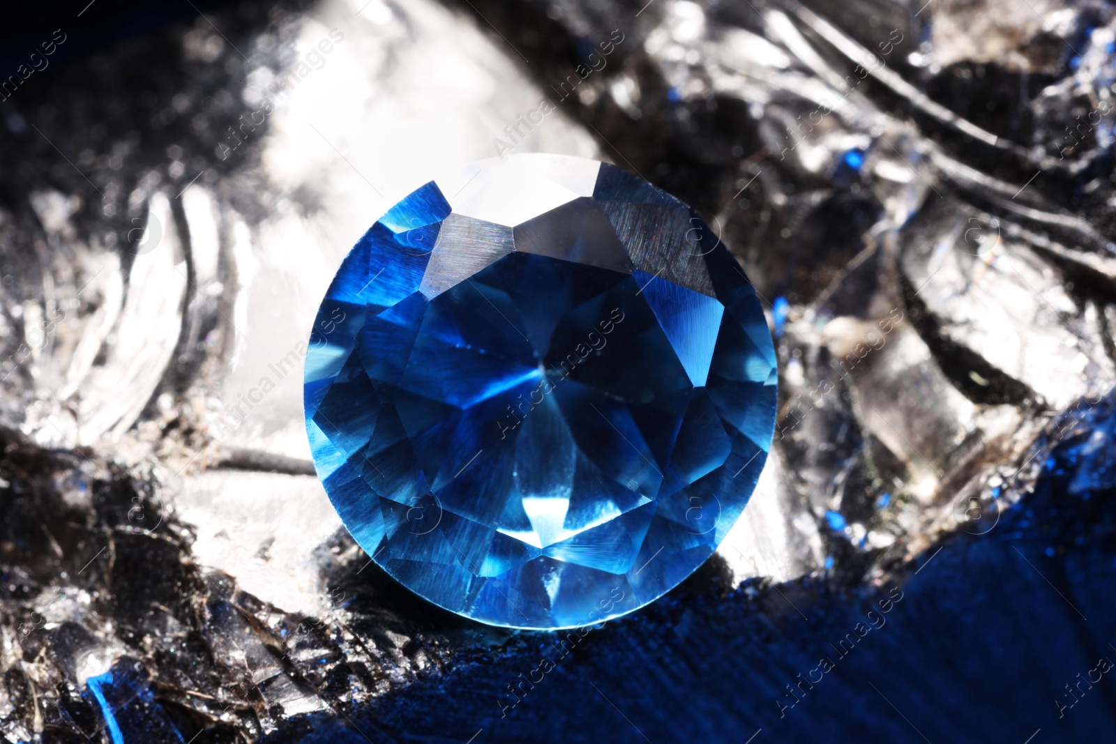 Photo of Beautiful shiny light blue gemstone on stone, closeup