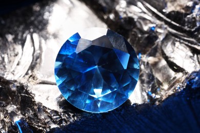 Photo of Beautiful shiny light blue gemstone on stone, closeup