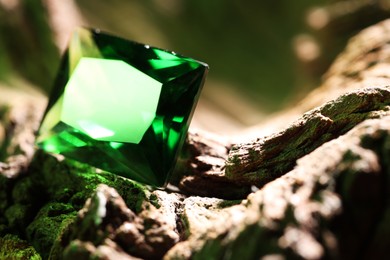 Photo of Beautiful shiny green gemstone on stone, closeup