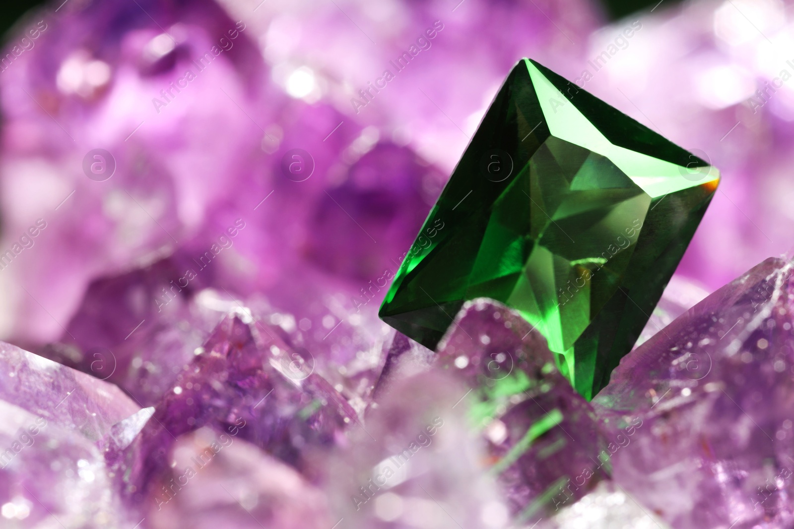 Photo of Beautiful shiny green gemstone on natural amethyst, closeup