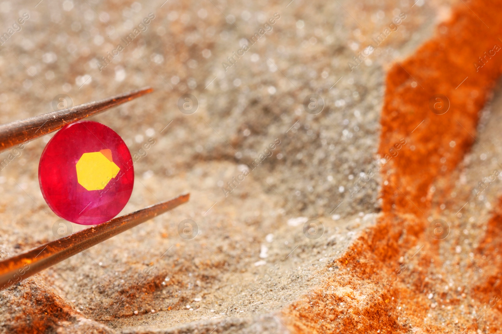 Photo of Tweezers with beautiful pink gemstone on stone, closeup. Space for text