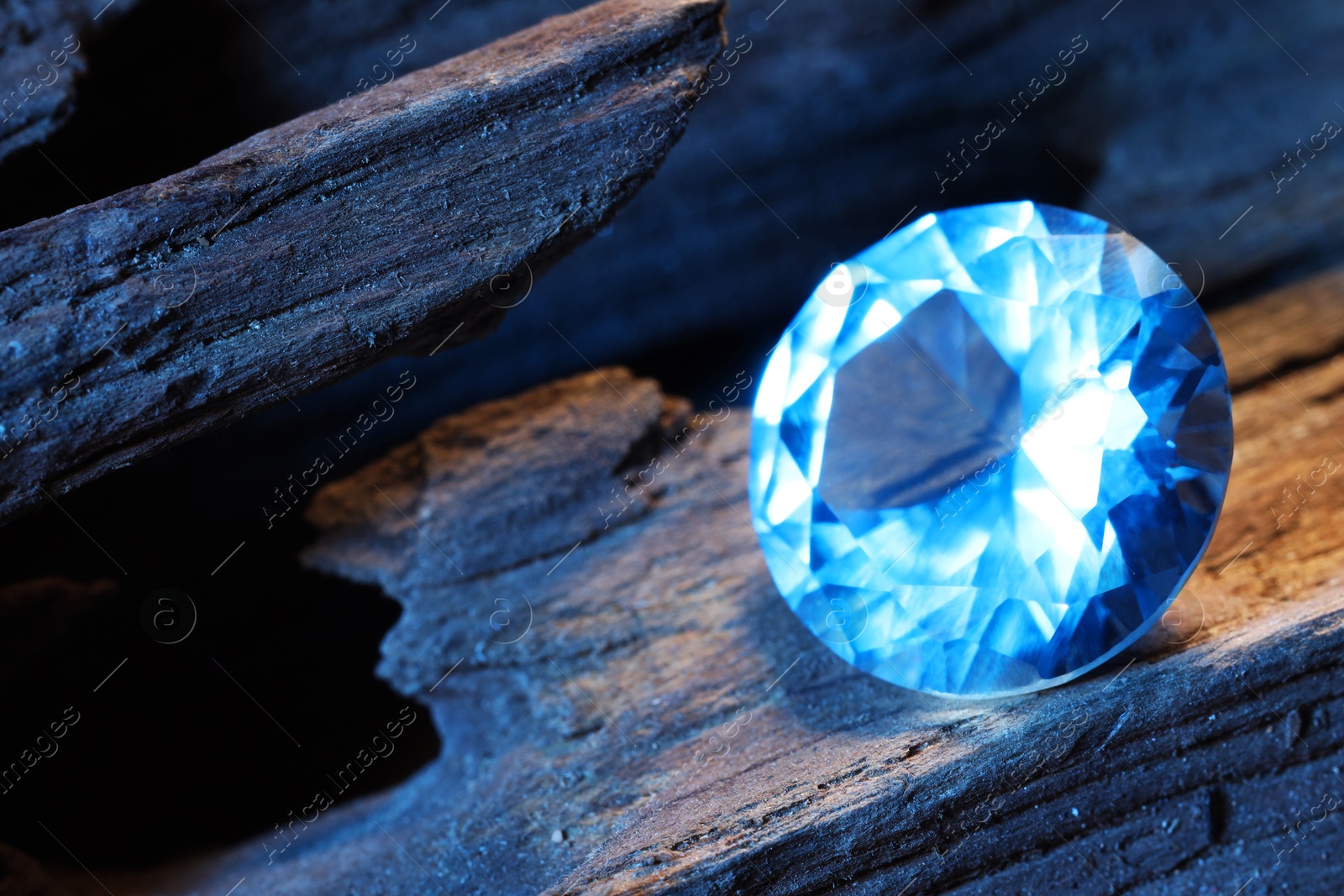 Photo of Beautiful shiny light blue gemstone on stone, closeup