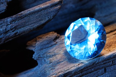 Photo of Beautiful shiny light blue gemstone on stone, closeup