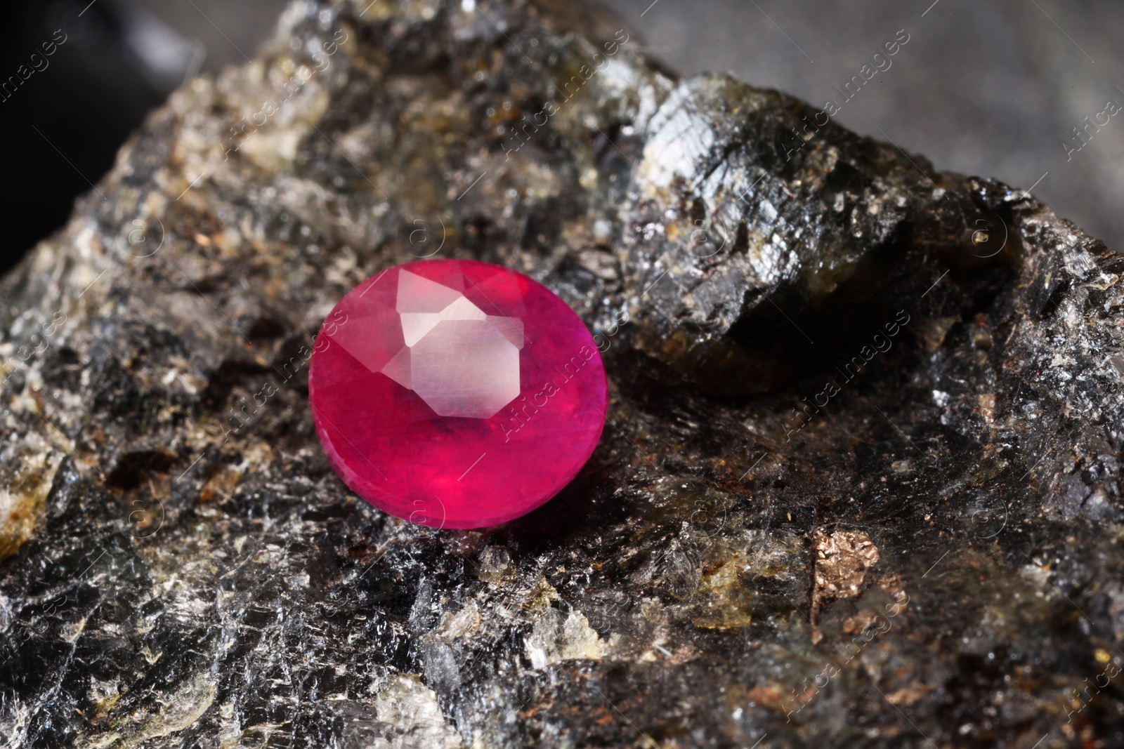 Photo of One beautiful shiny pink gemstone on stone