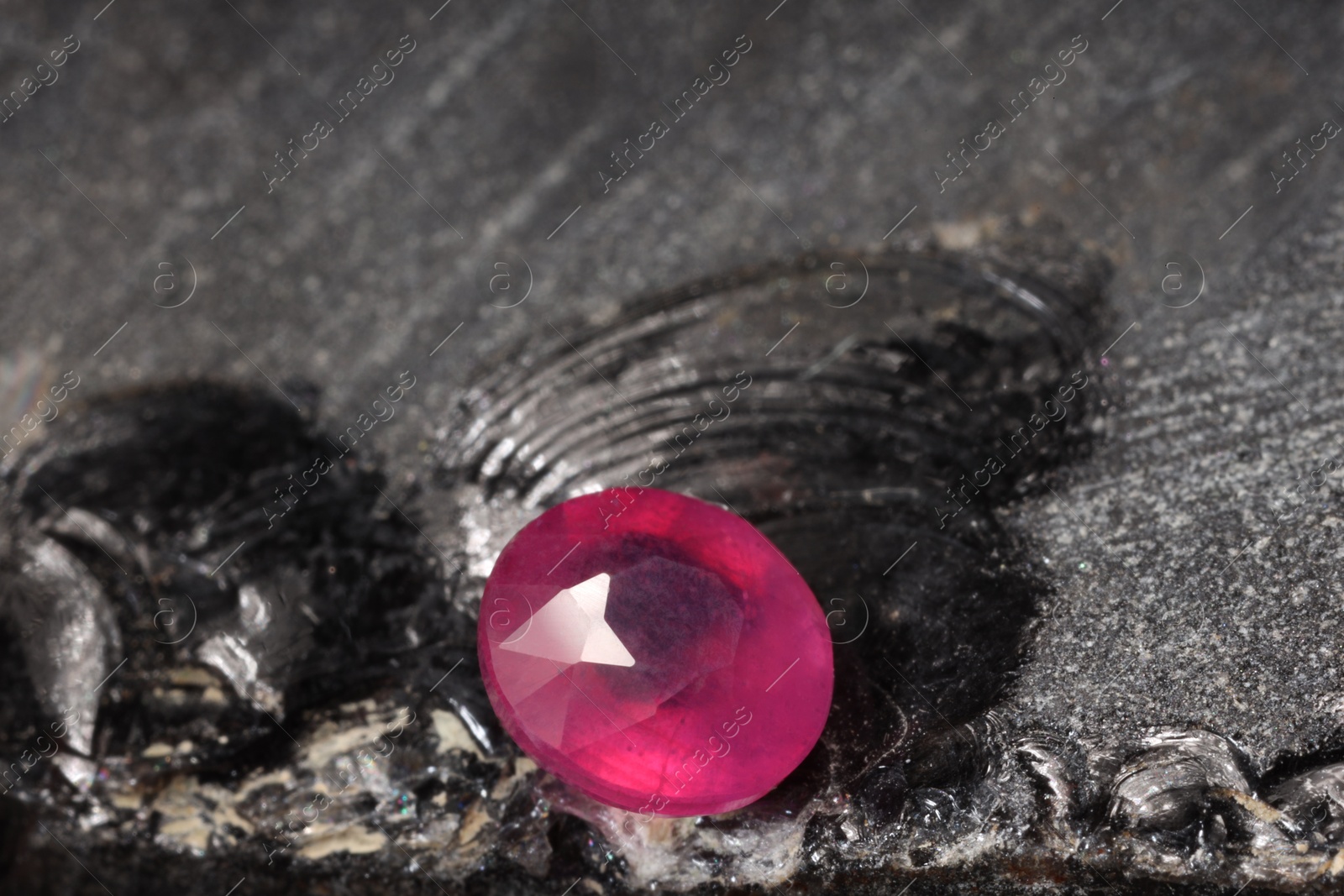 Photo of Beautiful shiny pink gemstone on stone, space for text