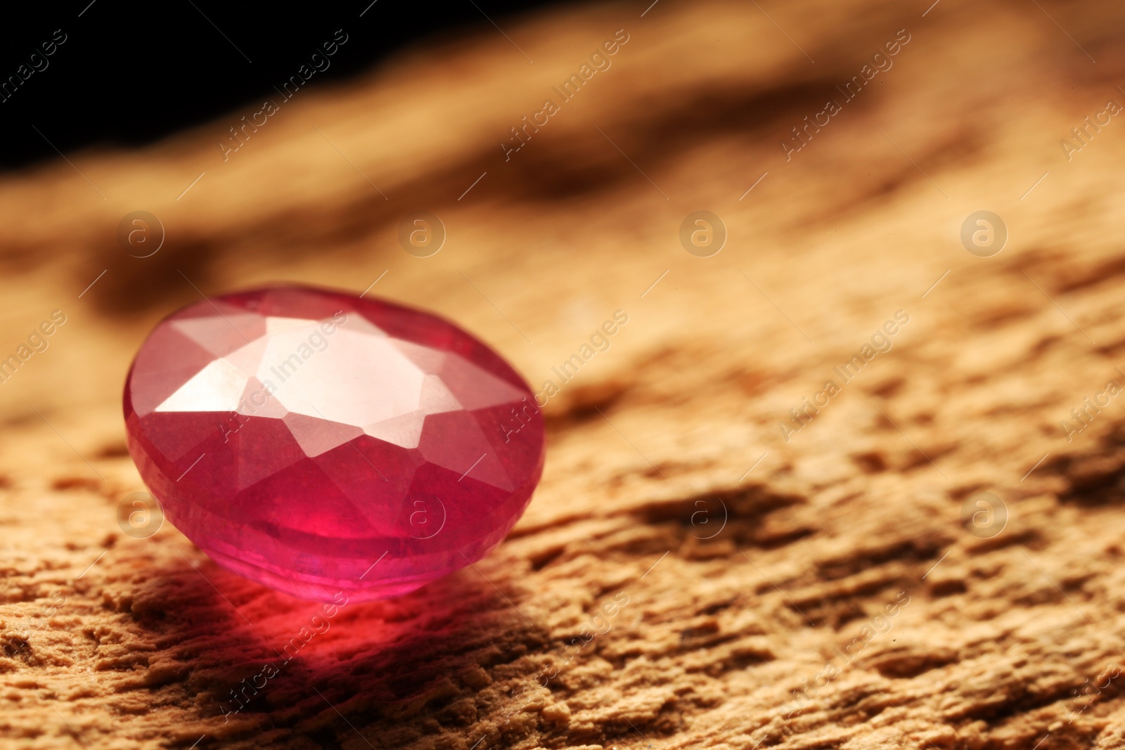 Photo of Beautiful shiny pink gemstone on stone, closeup. Space for text