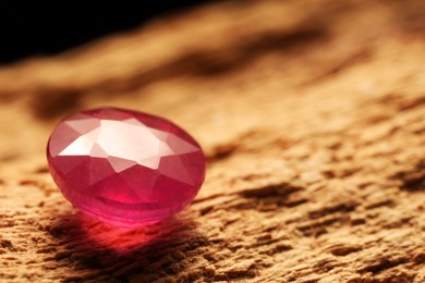 Photo of Beautiful shiny pink gemstone on stone, closeup. Space for text