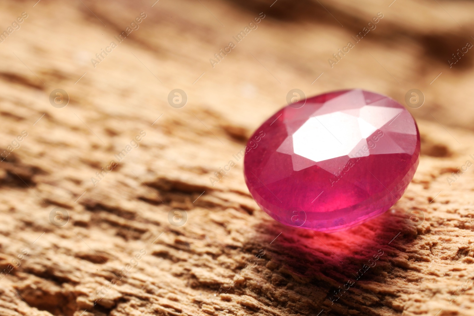 Photo of Beautiful shiny pink gemstone on stone, closeup. Space for text