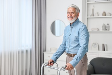 Photo of Senior man using walking frame at home. Space for text