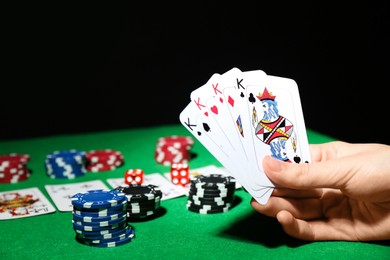 Photo of Poker game. Woman with playing cards at green table, closeup