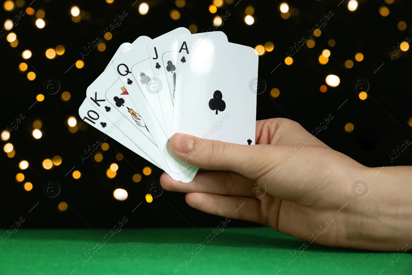 Photo of Poker game. Woman with playing cards at green table, closeup