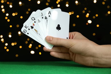 Poker game. Woman with playing cards at green table, closeup