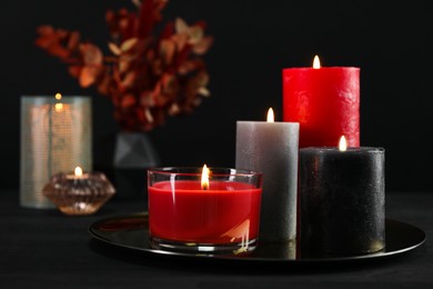 Photo of Beautiful burning candles and decor on black table, closeup