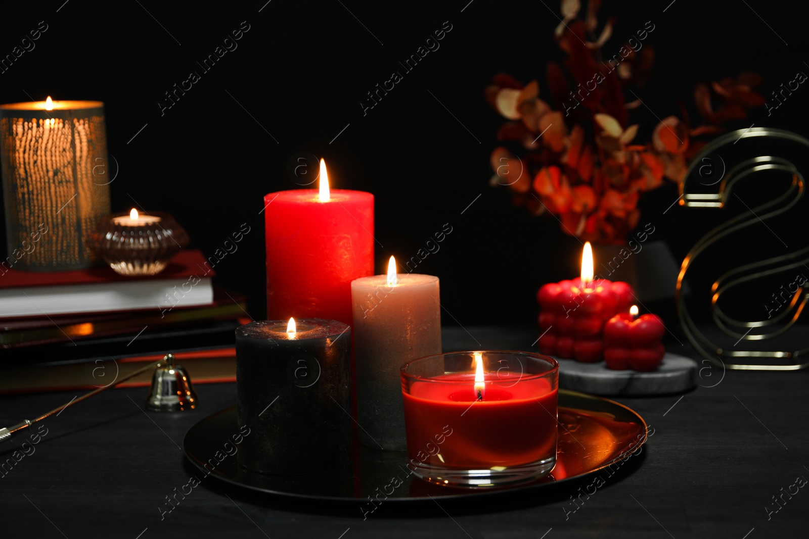 Photo of Beautiful burning candles and decor on black table