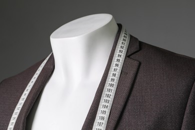 Photo of Male mannequin with brown jacket and measuring tape on grey background, closeup