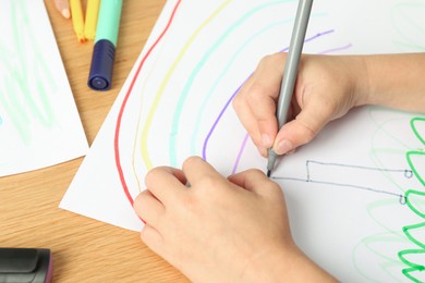 Photo of Boy drawing picture at wooden table, closeup