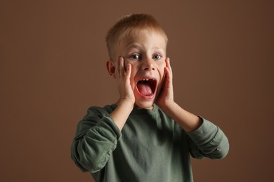 Photo of Scared little boy screaming on brown background