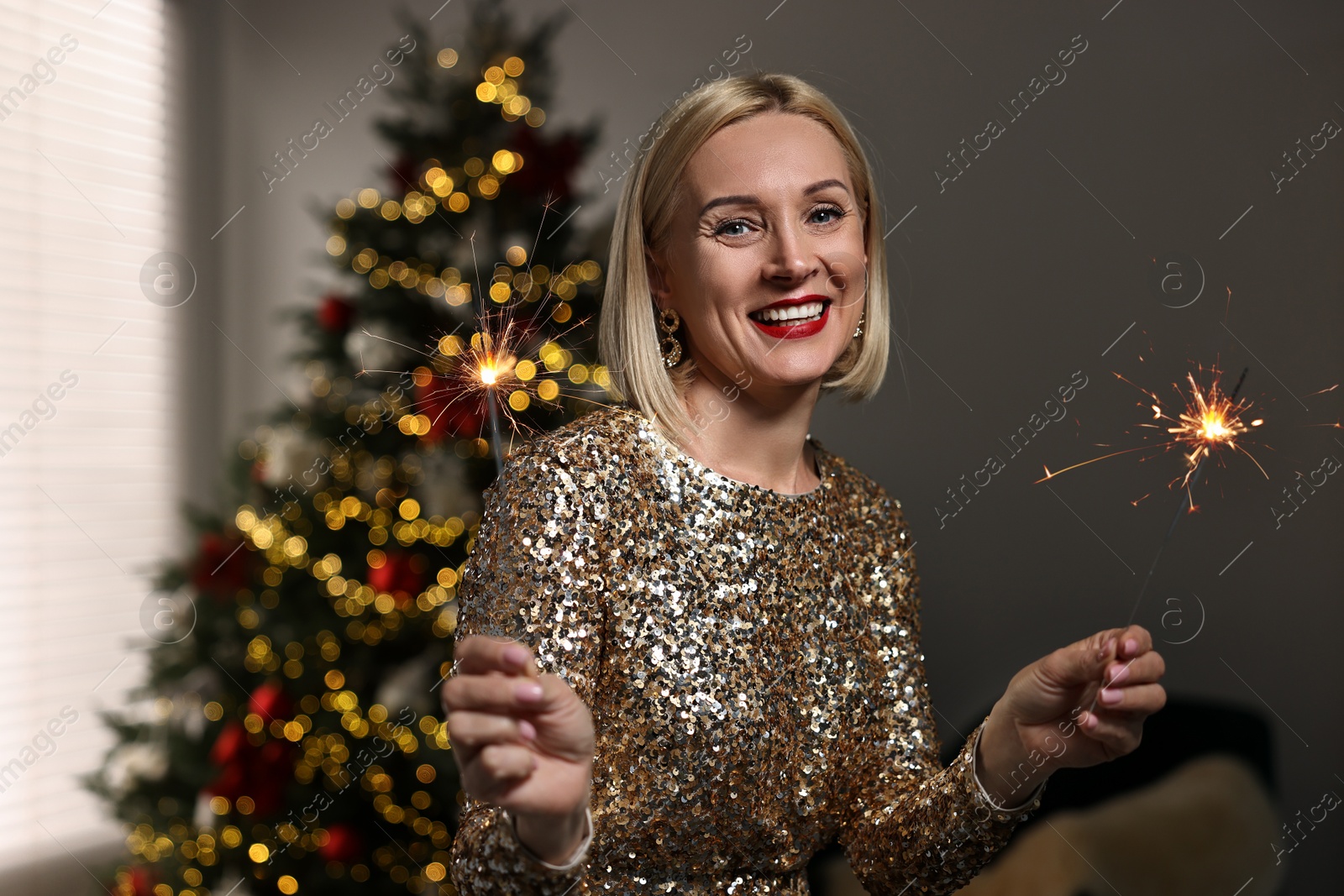 Photo of Smiling woman with sparklers celebrating Christmas at home