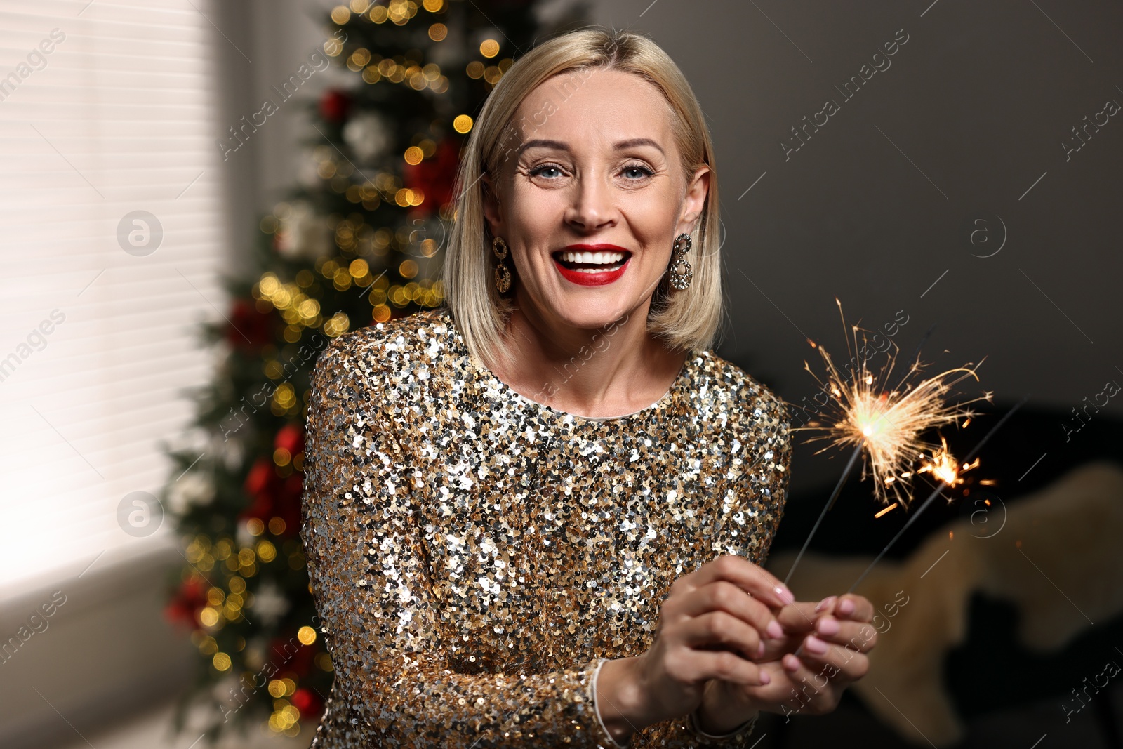 Photo of Smiling woman with sparklers celebrating Christmas at home