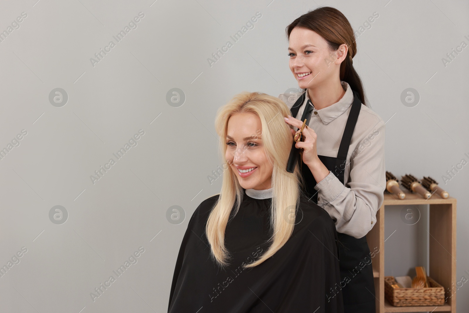 Photo of Hair cutting. Professional hairdresser working with client in salon, space for text