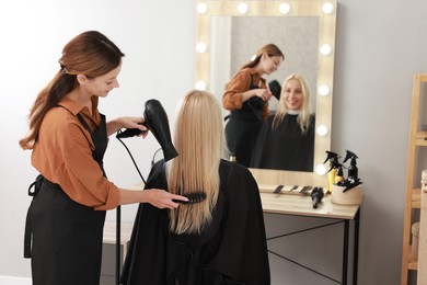 Photo of Hairdresser blow drying client's hair in salon