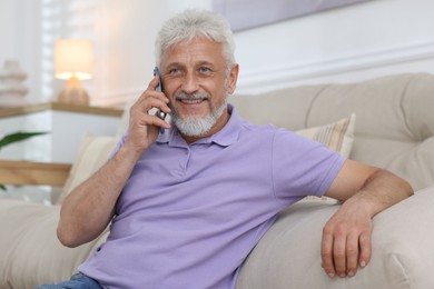 Photo of Smiling senior man talking on phone at home