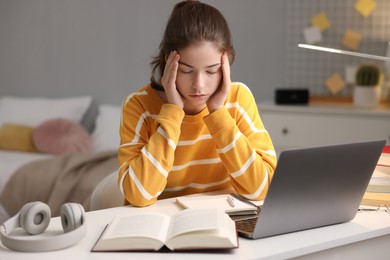 Photo of Tired student preparing for exam at table indoors