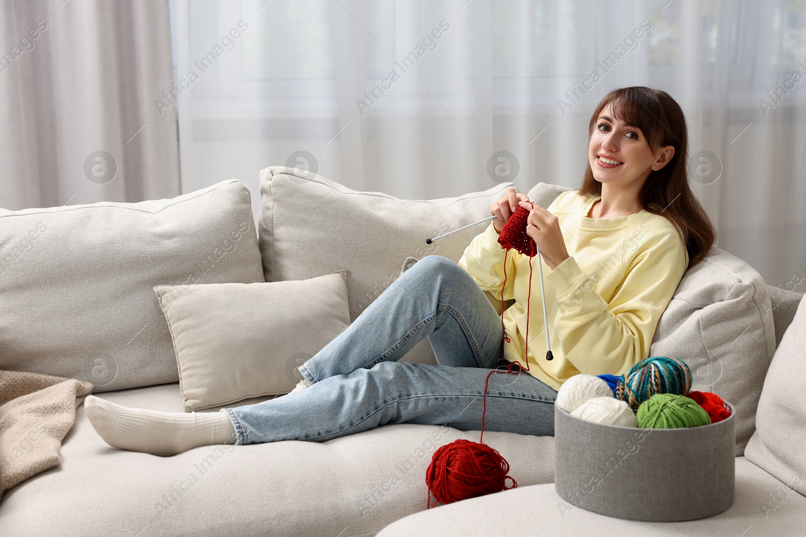 Photo of Beautiful woman knitting on sofa at home