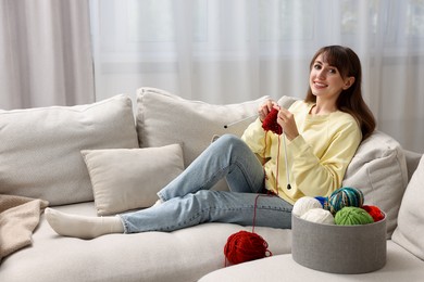 Photo of Beautiful woman knitting on sofa at home