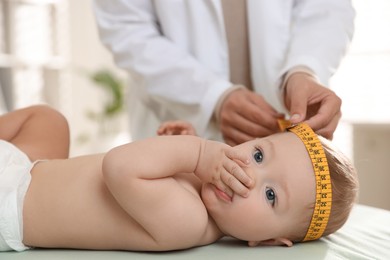 Photo of Pediatrician measuring little baby's head in clinic, closeup