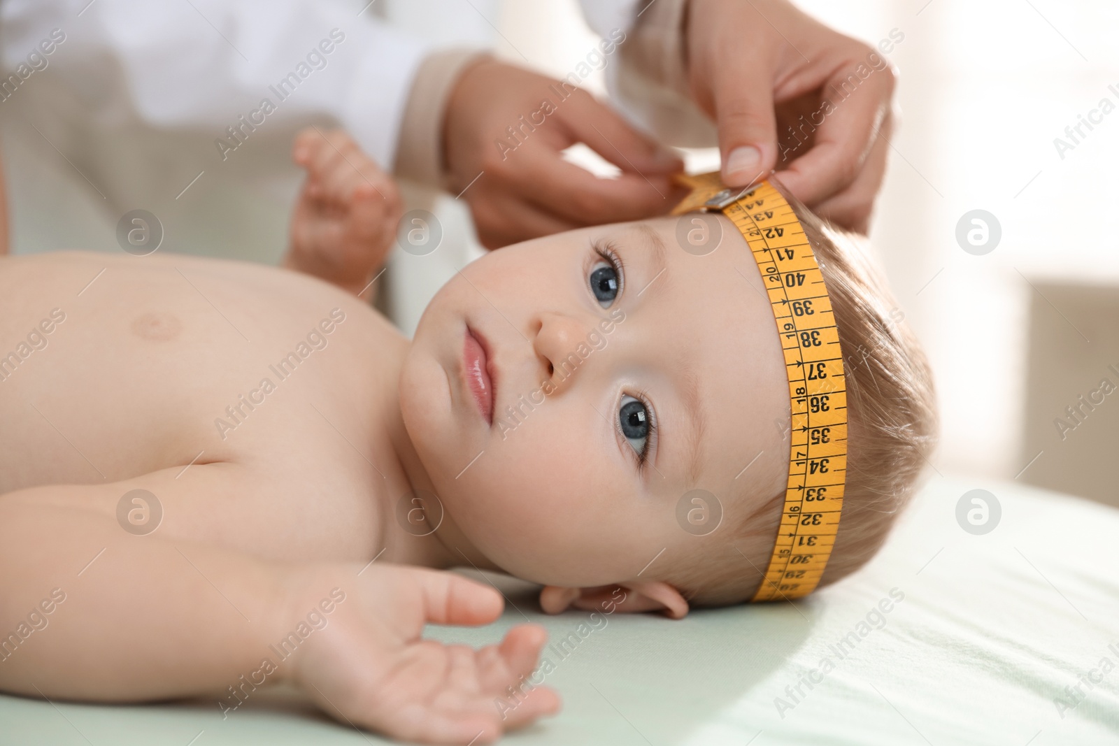 Photo of Pediatrician measuring little baby's head in clinic, closeup