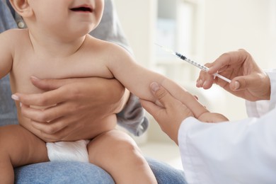 Photo of Pediatrician vaccinating little baby in clinic, closeup