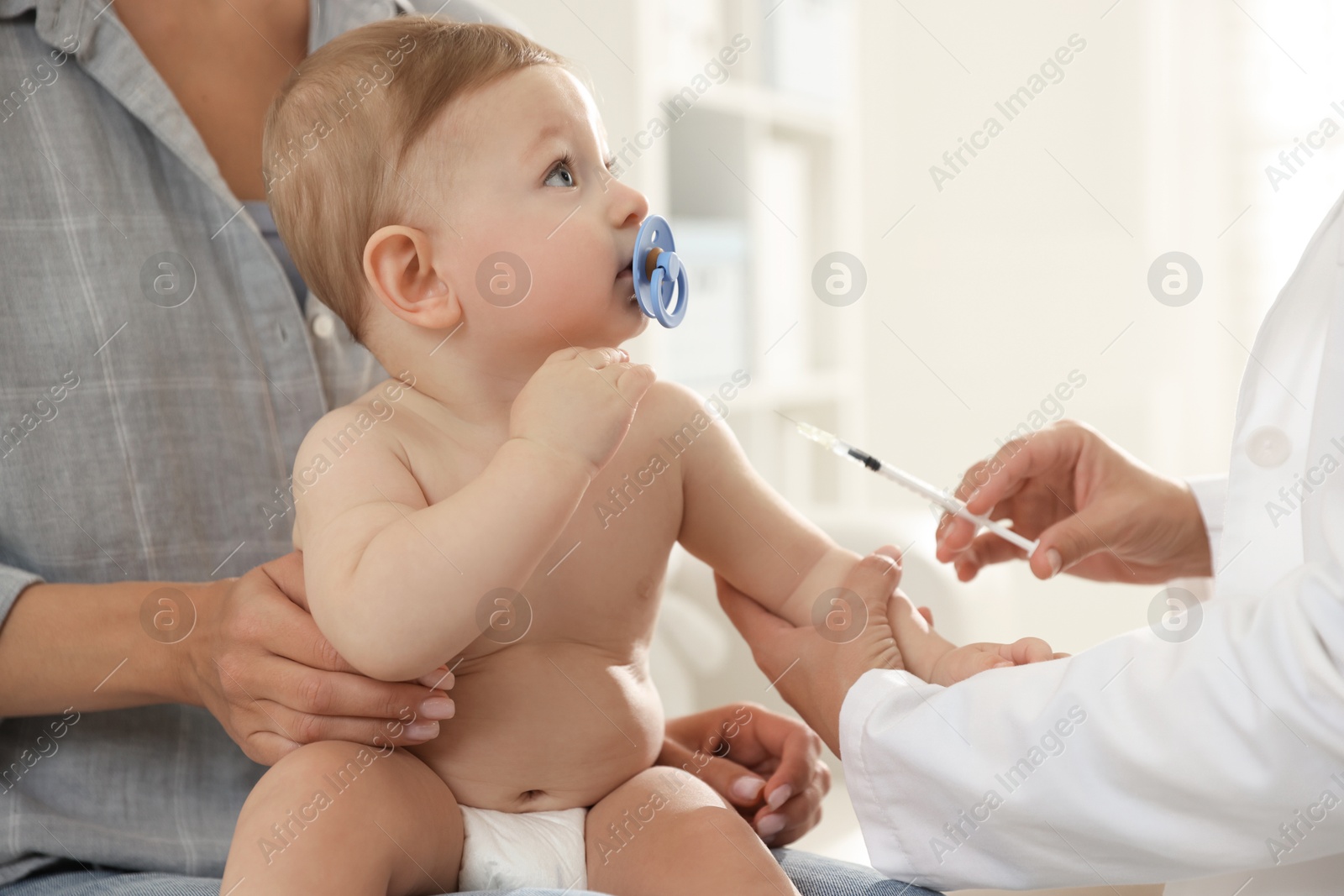 Photo of Pediatrician vaccinating little baby in clinic, closeup