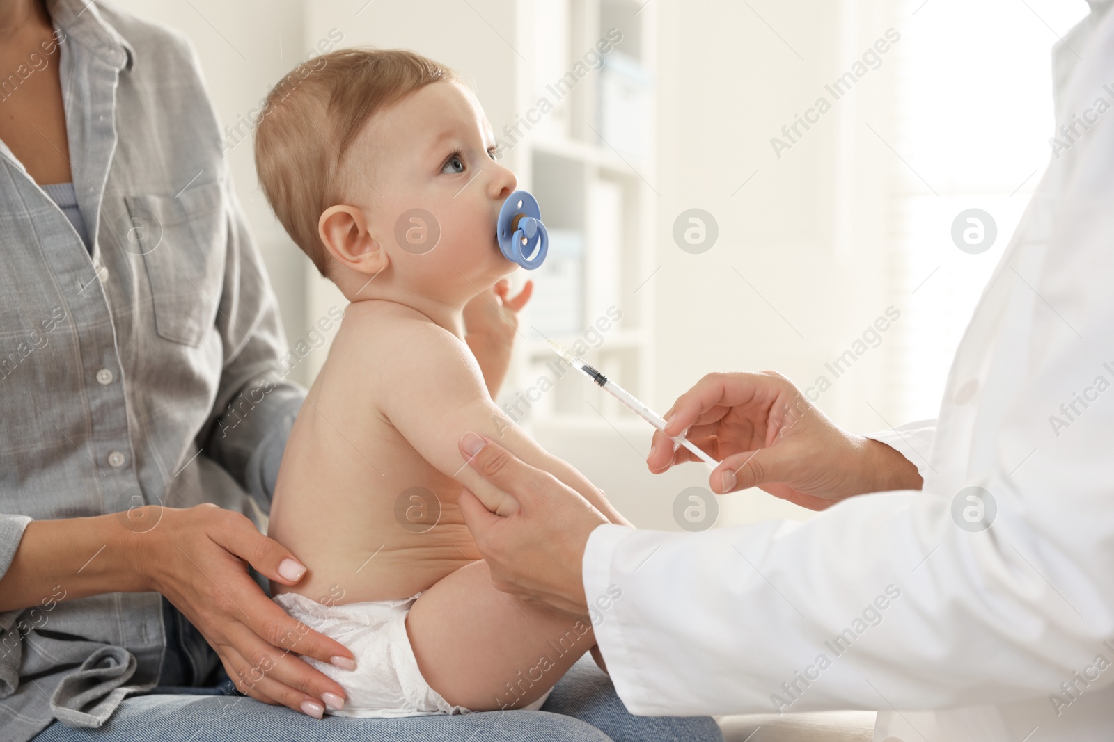 Photo of Pediatrician vaccinating little baby in clinic, closeup