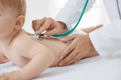 Photo of Pediatrician examining little child with stethoscope in clinic, closeup. Checking baby's health