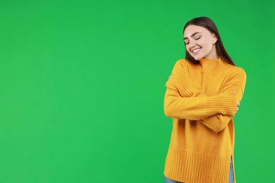 Photo of Charming young woman hugging herself on green background. Space for text