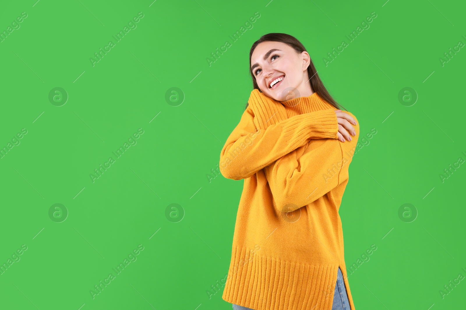 Photo of Charming young woman hugging herself on green background. Space for text