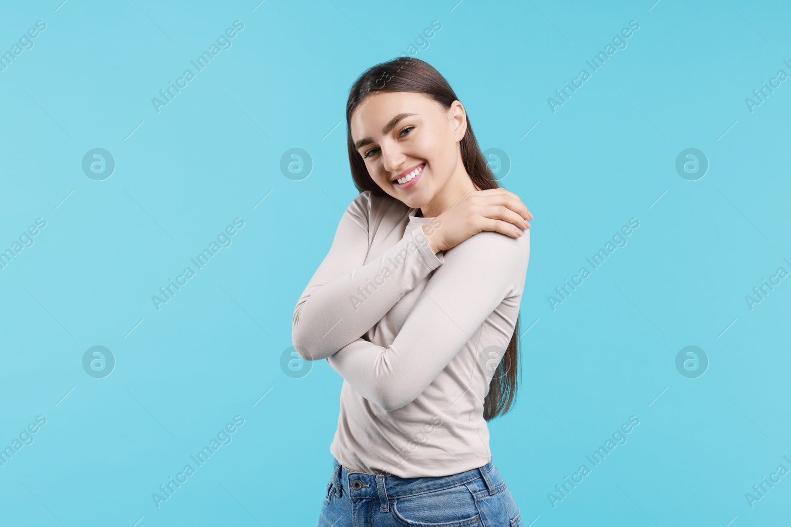 Photo of Charming young woman hugging herself on light blue background