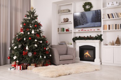 Beautifully decorated Christmas tree near fireplace in room. Festive interior design