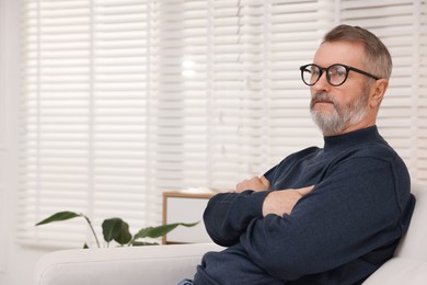 Photo of Mature man with crossed arms at home. Space for text