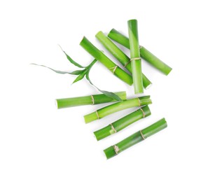 Pieces of decorative bamboo plant and green leaves isolated on white, top view