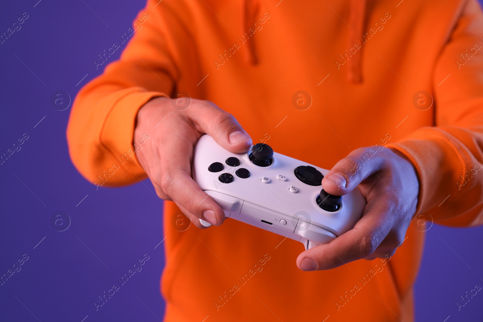 Photo of Man playing video games with controller on violet background, closeup