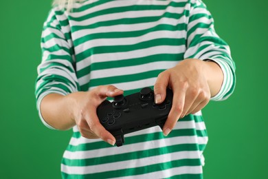 Photo of Woman playing video games with controller on green background, closeup