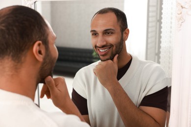 Photo of Smiling man looking at mirror at home